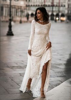 a woman in a white dress is walking down the street