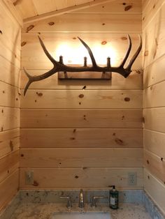 a bathroom with a sink and deer antlers mounted to the side of it's wall