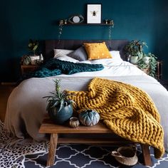 a bedroom with green walls, white bedding and yellow throw blanket on the end table