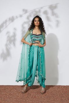 Aqua bustier embroidered with thread, tubes, pearls, beads & mirrors paired with pleated dhoti pants and mirror embellished net cape. This exquisite set is truly a work of art, with intricate embroidery and embellishments that sparkle and catch the eye. The bustier and dhoti pants are paired perfectly, while the net cape adds a touch of elegance and luxury. You'll feel like a true fashion icon in this stunning ensemble. Colour : AQUA Fabric : CREPE AND NET Embroidery details : HAND EMBROIDERY Co Festive Set With Sheer Dupatta And Cape Sleeves, Bollywood Sets With Sheer Dupatta And Cape Sleeves, Festive Bollywood Anarkali Set With Cape Sleeves, Reception Salwar Kameez With Mirror Work, Salwar Kameez With Mirror Work For Reception, Reception Salwar Kameez With Mirror Work In Traditional Drape, Bollywood Style Sets With Cape Sleeves For Eid, Bollywood Style Sharara With Cape Sleeves For Festivals, Festive Bollywood Sharara With Cape Sleeves