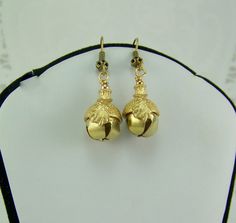 "These gold toned jingle bell acorn earrings are inspired by the book The Belgariad, by David Eddings. CeNedra, a character in the book loved these earrings. An excerpt from the book states that \"Ce'Nedra's mother wore the two acorn earrings of which her daughter was so fond, and the two tiny clappers inside them gave off that faint, musical tinkle ...\" They crossed the last band of open fields and rode in under the ancient, mossy oaks. The leaves had fallen to the chill winds of winter, and the bare limbs of the huge trees were starkly etched against the sky. A peculiar change came over Ce'Nedra as they entered the Wood. Although it was still not really warm, she pushed back the hood of her cloak and shook out her coppery curls, causing her tiny, acorn-shaped gold earrings to tinkle mus The Belgariad, David Eddings, Winds Of Winter, Oak Leaf Earrings, Acorn Earrings, Bell Earrings, Good Luck Symbols, Oak Leaf, Nature Inspired Jewelry