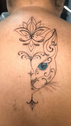 the back of a woman's neck with a cat and flower tattoo on it