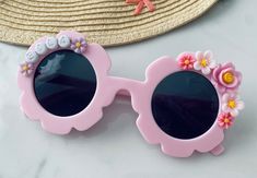 Brand new to MeaganElizabethCo, custom pastel flower sunnies! We are so excited to be adding other fashion accessories to our shop for your littles! And who could pass up these adorable pink flower sunnies?!? These sunnies are the perfect accessory for any vacation, photoshoot, birthday party or everyday where! These sunnies can be customized by YOU for your little fashionista! Step 1: Pick your sunnies and font color   Step 2: Use PERSONALIZE BOX at check out to note NAME, WORD(S) A STANDARD SUNNIES ORDER WILL COME WITH YOUR PERSONALIZED WORD/NAME/SAYING AND FLOWER EMBELLISHMENTS VARYING IN SIZE AND COLOR BASED ON FONT SELECTION AND LENGTH OF PERSONALIZATION  PRODUCT DETAILS:  SUNGLASSES ARE SIZED FOR TODDLERS/YOUNG KIDS UP TO AGE 10 *All letters are capitalized  Lightweight but sturdy. A Pink Personalized Adjustable Sunglasses, Cute Pink Sunglasses For Spring, Spring Gift Sunglasses With Uv Protection, Customizable Pink Sunglasses For The Beach, Spring Gift Sunglasses With Gradient Lenses, Personalized Pink Sunglasses For Beach, Spring Gift Sunglasses With Tinted Lenses, Spring Gift Sunglasses With Adjustable Fit, Spring Gift Adjustable Sunglasses