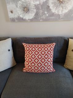 a couch with two pillows on it and a painting hanging above the couch in front of it