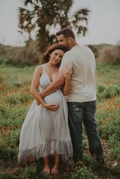 a pregnant woman and man standing in a field