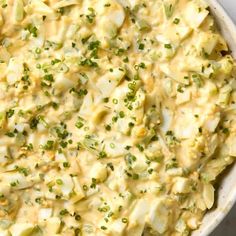 a casserole dish with potatoes and green onions in a white bowl on a table