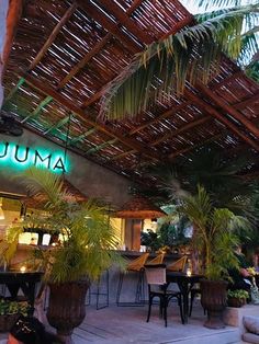 the outside of a restaurant with tables and chairs under a bamboo roof that reads luma