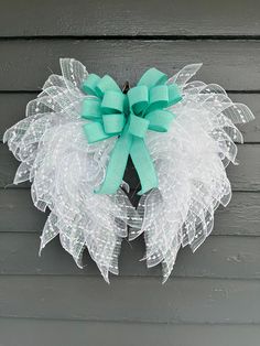 a green and white wreath hanging on the side of a building with a blue bow