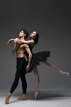 two ballerinas in black tutus, one holding the other