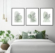 three framed art prints on the wall above a bed with pillows and plants in vases