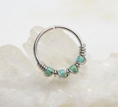 a close up of a ring with beads on it sitting on top of a rock