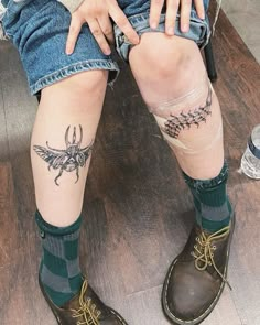 a person sitting on the ground with their legs crossed and tattoos on her leg,