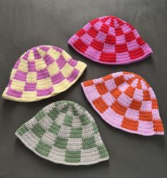 three crocheted hats sitting next to each other on top of a gray surface