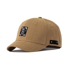 a tan hat with black patches on the front and side panel, featuring an embroidered patch