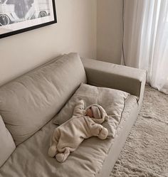 a stuffed animal laying on top of a couch in a living room next to a window