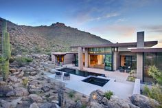 a house in the desert surrounded by rocks and cacti, with a pool