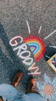 someone is standing on the sidewalk with chalk writing in front of them and a book