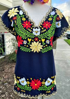 "Step into the realm of bohemian elegance with our stunning Navy Blue 100% Linen blouse, exquisitely crafted by skilled artisans in Mexico.  Adorned with delicate colorful floral silk thread embroidery, this short-sleeve blouse exudes a sense of effortless beauty and artisanal charm.  The scalloped yellow finish adds a touch of whimsical flair, elevating the bohemian aesthetic to new heights.  Each stitch is a testament to the craftsmanship and attention to detail that goes into creating this un Silk Thread Embroidery, Bohemian Aesthetic, Effortless Beauty, Thread Embroidery, The Bohemian, Linen Blouse, Silk Thread, Bohemian Chic, Short Sleeve Blouse