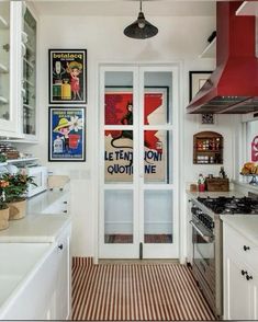 a kitchen with posters on the wall and an open door leading to another room that has a stove top oven in it