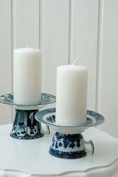 two white candles sitting on top of a blue and white plate