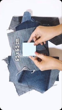 a person is holding a business card in their left hand and some jeans on the floor