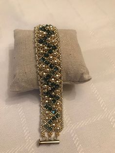 the beaded bracelet is sitting on top of a pillow with a gold bar in it