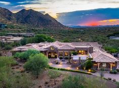 an aerial view of a home in the desert with mountains in the background at sunset