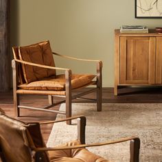 a living room with two leather chairs and a wooden cabinet in the corner next to it