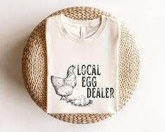 "Local Egg Dealer Shirt. This cute Easter Chicken design is the perfect tshirt for wearing this Easter. Buy it for yourself or give it as the perfect gift for teacher, mom or chicken loving mama.  Local Egg Dealer Shirt, Easter Shirt, Christian Easter Shirt, Happy Easter Shirt, Chicken shirt, Chicken Gifts for Farmer, Mama Easter Shirt ⭐️HOW TO ORDER⭐️ Select your quantity of shirts in the specific colour/size and click \"ADD TO BASKET\"   Repeat as needed by returning to the listing button to a Easter Clothing, Dark Blue Sweatshirt, Chicken Design, Easter Chicken, Chicken Shirt, Chicken Gifts, Chicken Shirts, Teacher Mom, Gifts For Farmers