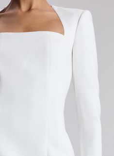 the back of a woman's white dress with an open shoulder and long sleeves