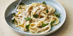 a bowl filled with pasta and parsley on top of a table next to a fork