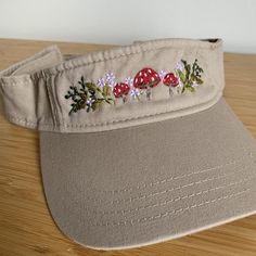 a hat with embroidered flowers on it sitting on top of a wooden table