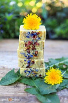 a soap bar with flowers on top of it next to some leaves and yellow flowers