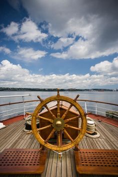 a wooden deck with two benches and a steering wheel on the front of a boat