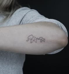 a woman's arm with three origami elephants tattooed on the left arm