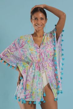 Stylish and easy to wear coverup. A playful flower print with purples and pops of lime on white. Turquoise tassels. Drawstring waist. This elegant and modern caftan works as beachwear, loungewear, or layered over a camisole for a casual look. Tie it open for a kimono style. Beachwear V-neck Cover-up With Tassels, Vacation V-neck Kaftan With Tassel Ties, Green Floral Print Summer Cover-up, Sleeveless Beachwear Cover-up For Loungewear, Multicolor V-neck Cover-up For Pool, Multicolor Poolside Cover-up For Resort Season, Bohemian Multicolor Tassel Cover-up, Blue Tasseled Swimwear For Poolside, White Tropical Cover-up For Resort Season