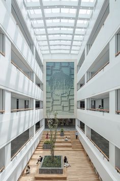 an empty building with lots of windows and wood flooring in the center is a large planter filled with green plants