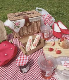 the picnic is set out on the grass with strawberries, bread and jams