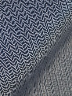 an abstract pattern made up of wavy lines on a sheet of white fabric with blue and grey colors