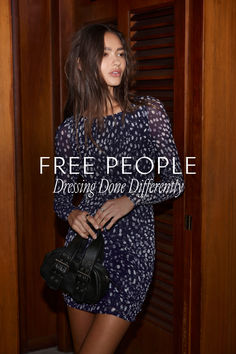 a woman standing in front of a wooden door holding a handbag with the words free people driving done differently