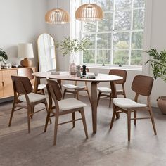 a dining table with four chairs and a mirror in the corner, next to a potted plant