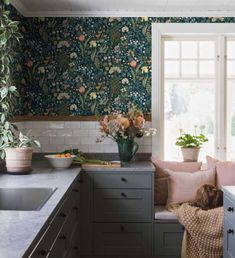 a kitchen filled with lots of counter top space and flowers on the wall behind it