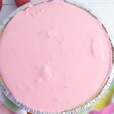 there is a pie with pink icing on the top and two strawberries in the background