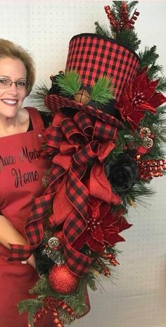 a woman standing next to a christmas wreath