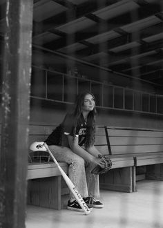 a woman sitting on a bench holding a baseball bat