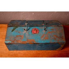 an old blue metal box sitting on top of a wooden table next to a wall