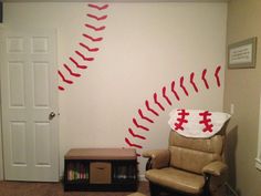 a room with a baseball wall decal and a recliner chair in the corner