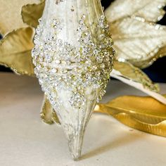 a glass vase sitting on top of a table next to a gold leafy plant