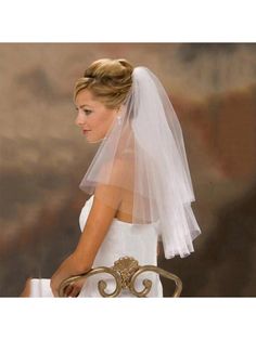 a woman wearing a wedding veil and sitting on a chair