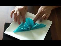 someone is folding an origami flower on a plate